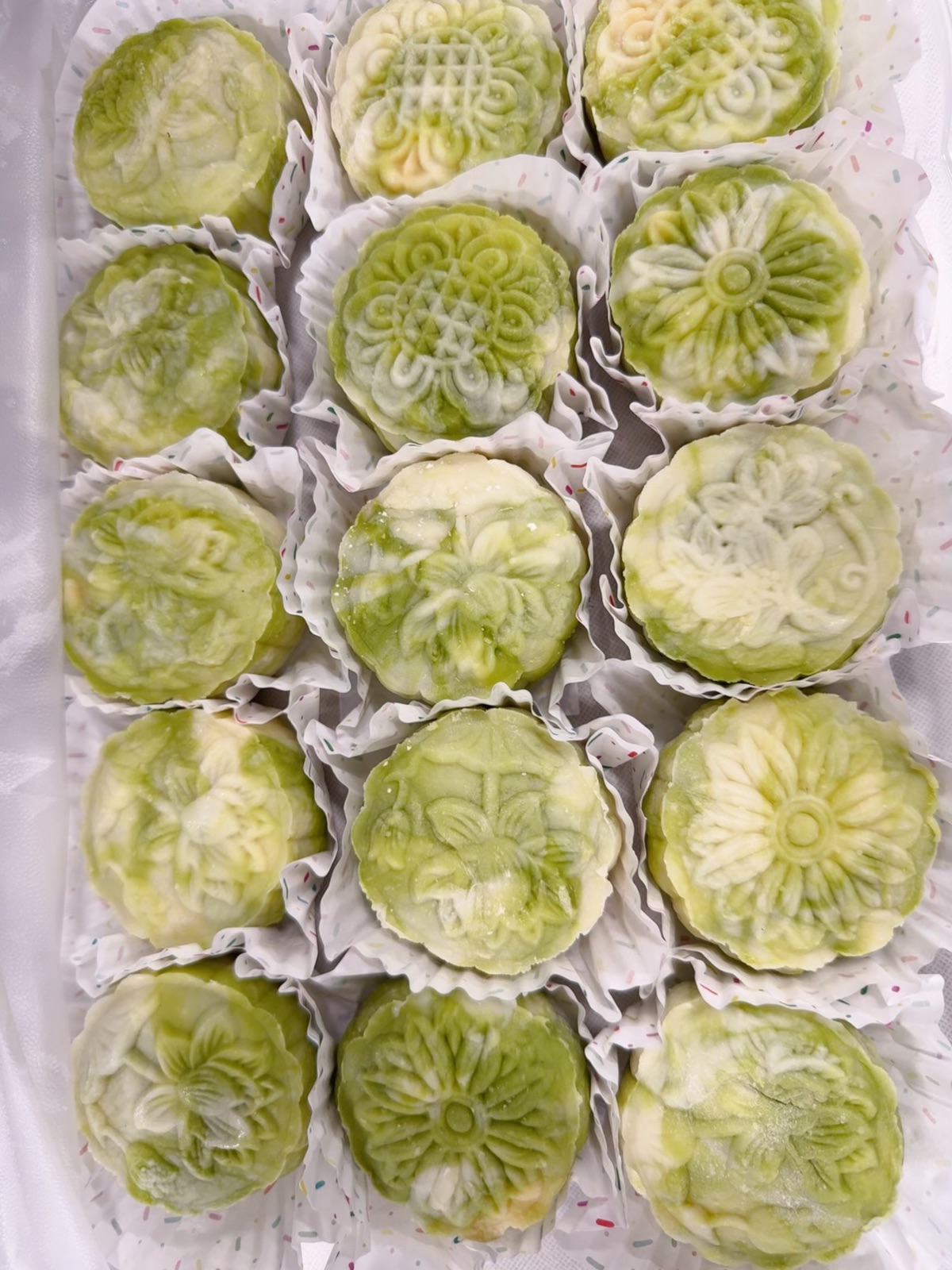 Homemade green and white mochi mooncakes arranged on a tray